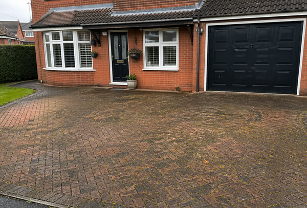 Block paving driveway in Northampton before cleaning, with weeds, moss and dark staining
