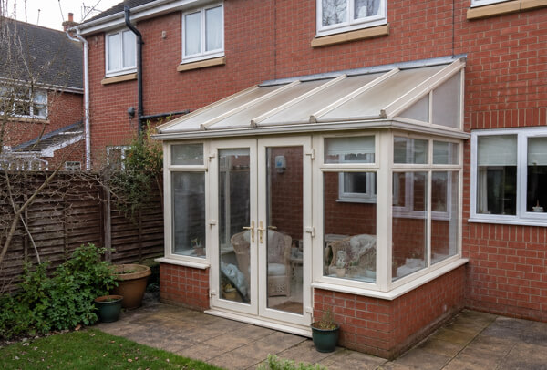 A conservatory with older white frames before they were repainted