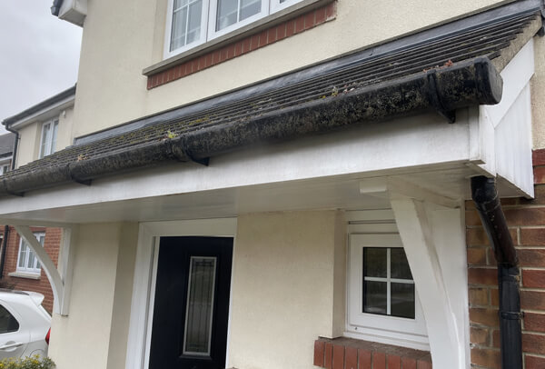Gutter and downpipe in Northampton before clearing, with blockage affecting drainage