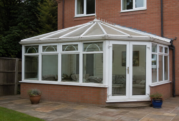 A conservatory with tired frames viewed from the garden