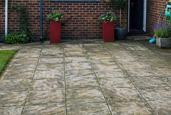 Patio in Northampton before cleaning, with dark staining, algae and built-up dirt on the slabs