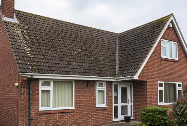 Roof in Northampton before cleaning, with moss, algae and weather staining on the tiles